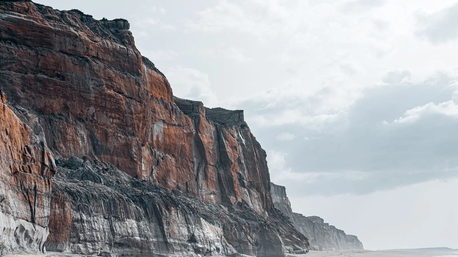 Tebing pantai menjulang di atas pasir yang tenang (foto ilustrasi)